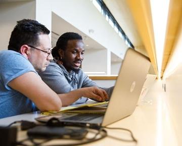 two students working on a computer in the library